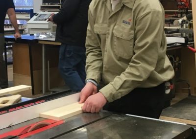 Student uses a saw to cut and measure wood