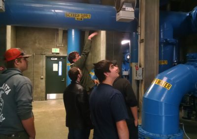 Students look at the pipes that carry water from outside into the water district facility