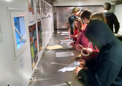 Students work with tape in the mobile lab to build their rockets
