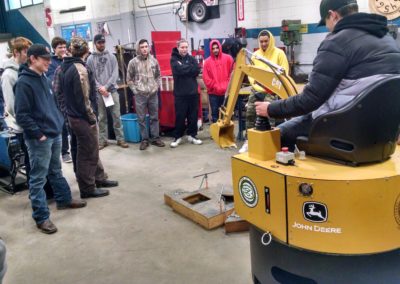 Student operating machinery while other students look on