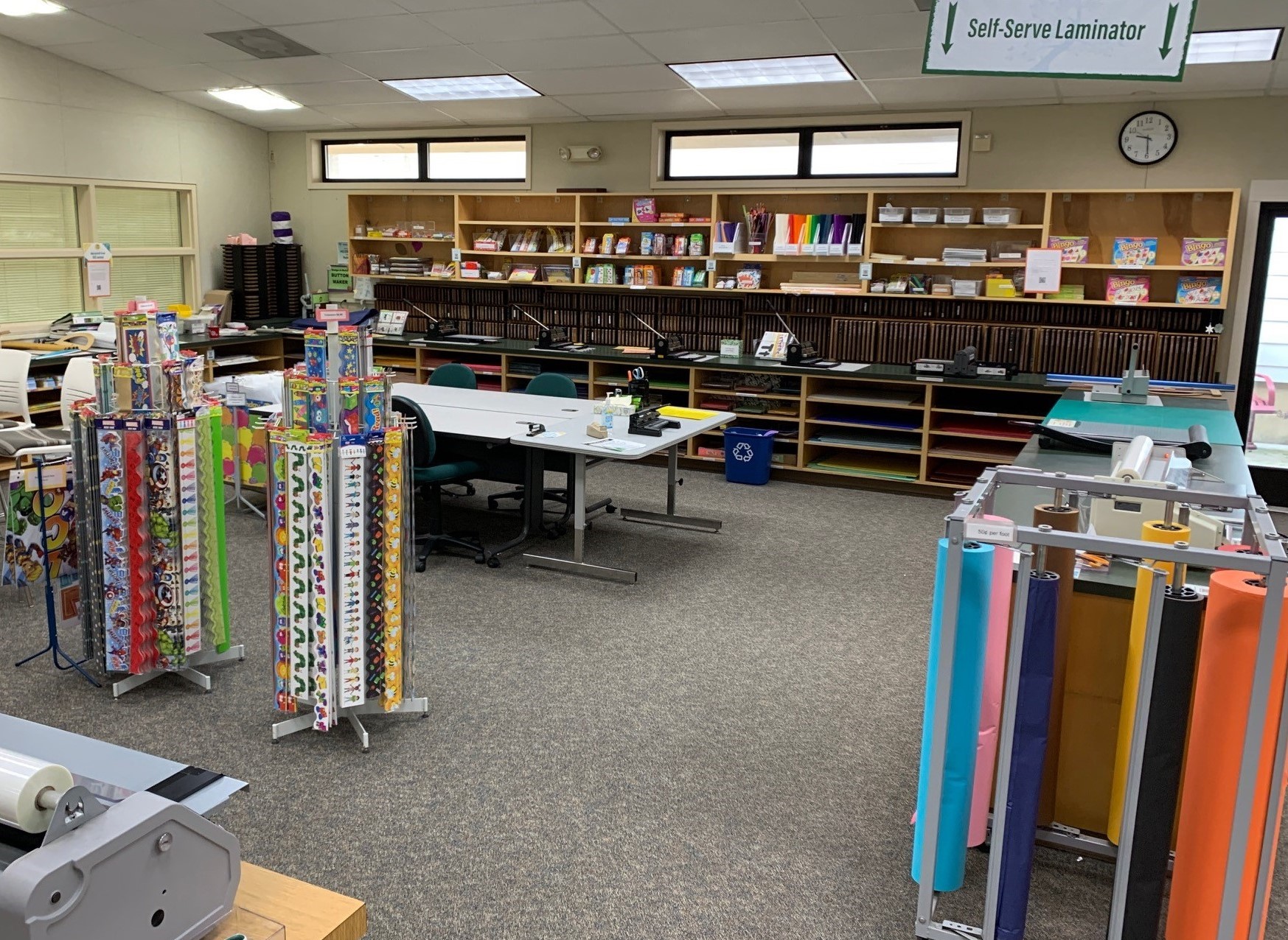Work space with laminators, die cuts, school supplies and colorful butcher paper.