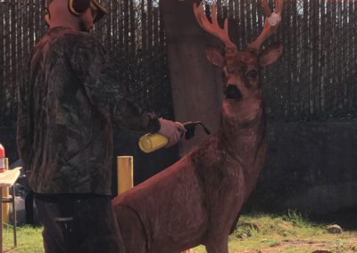 A chainsaw artist working on sculpting a buck