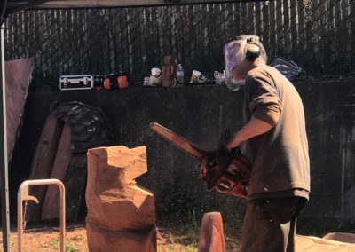 A chainsaw artist working on a small bear