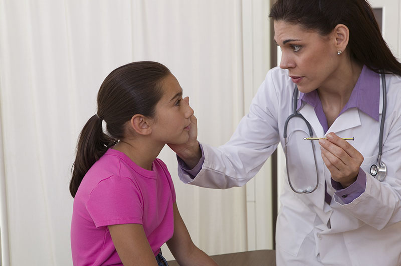 A school nurse ives a student a checkup