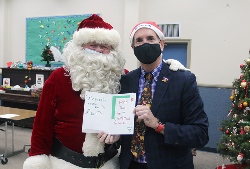 Santa and Kiwanis Henderson Center President John Friedenbach show off a letter they received from a class.