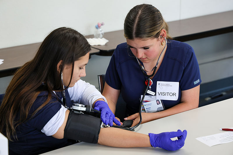 Two HESI students practice taking blood pressure readings.