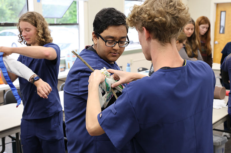 Two HESI students practice applying tourniquets