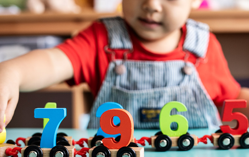 A young child playing with number trains