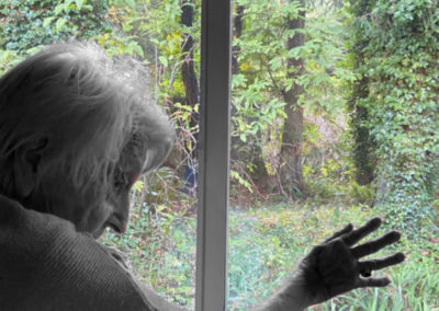 A photo of an old woman looking out a window